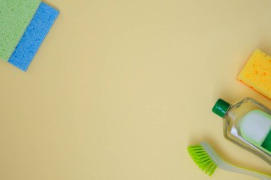 Sarı arka planda temizlik ürünleri. Mikro lif, sünger ve fırça. yaslanmış aksesuarlar. Üst te. Kopyalama alanı.