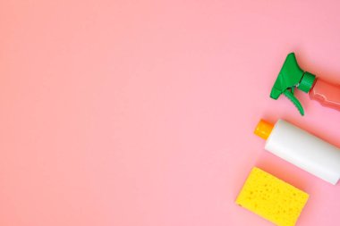 Pembe arka planda temizlik ürünleri. Deterjanlar ve sünger. Ev işleri ve ev konsepti. Üst te. Kopyalama alanı.