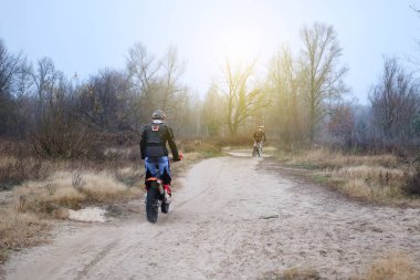 Spor ve aktif sağlıklı yaşam konsepti. Geç sonbahar parkta koruyucu motosikletçi. Ağaçlar arasında güneşli bir günde motosiklete binmek. Sağlıklı yaşam tarzı.
