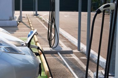Ekoloji dostu ulaşım konsepti. Enerji yüklüyor. Gri araba otoparkta elektrik şarj istasyonu şarj edilir. Elektrik ve otomobil.