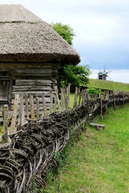 Ormanın yakınındaki evin yakınındaki köyde ahşap çit var. Mimarlık ve yaşamdaki otantik geleneksel kültür. Güneş ışığı, köydeki eski ahşap binalar. Dikey görünüm.