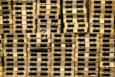 Pallets background. Stacks of brown rough wooden pallets at warehouse in industrial yard. Cargo and shipping concept.