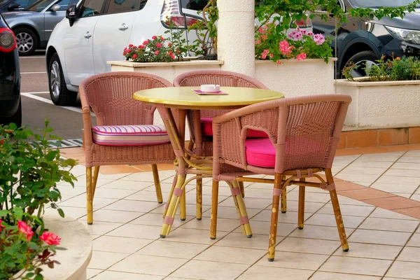Empty patio in summer in recreation. Pink table and armchairs on outdoor terrace of summer cafe.