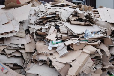Karton ve atık kağıt toplanır ve geri dönüşüm için paketlenir. Karton yığının içinde duruyor. Geri dönüşüm için kağıt kentsel çöp.