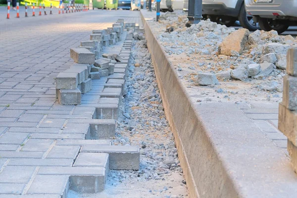 Konut kompleksinin yaya bölgesinde onarım çalışması. Mühendislik çalışıyor. İnşaatlarda kaldırım taşları döşeme, kentsel yeraltı iletişimi.