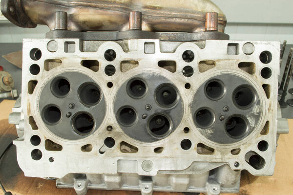 Bottom view of the V6 internal combustion engine block head, which is lying on a table in the car repair shop