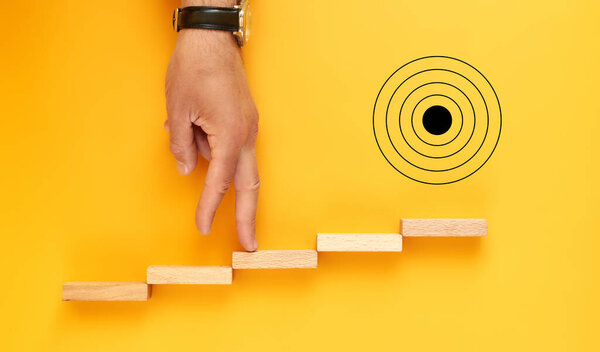 concept of movement to the goal. male hand with wooden blocks in the form of stairs