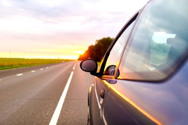 Araba yolculuğu konsepti. Gün batımında hareket eden bir arabanın parçası.