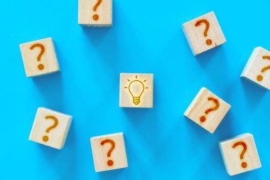 Sorun ve çözüm. Soru işaretli tahta küpler ve bir fikri sembolize eden ampullü küp.