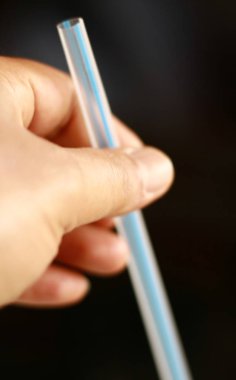 Birisi plastik pipet tutar.