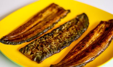 Yılan balığı balık veya unagi beyaz arka plan ile sarı plaka üzerinde. Pişirmeye hazır. 