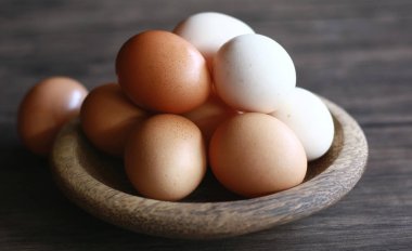 Tavuk yumurtası (kahverengi) ve kampong tavuk yumurtası (beyaz) ahşap plaka üzerinde.