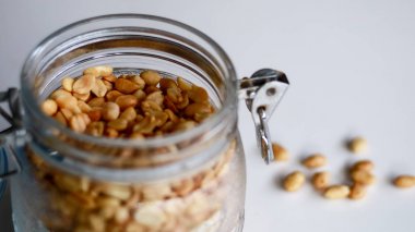 Beyaz arka planda bir kavanozda kızarmış fıstık.