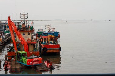 Jakarta, Endonezya - 21 Nisan 2019: Muara Angke Limanı'nda çöpleri temizlemek için çalışan bir ekskavatör, Kuzey Jakarta.