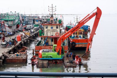 Jakarta, Endonezya - 21 Nisan 2019: Muara Angke Limanı'nda çöpleri temizlemek için çalışan bir ekskavatör, Kuzey Jakarta.