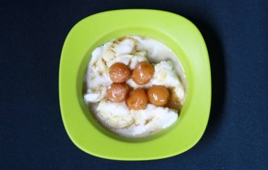 Siyah arka plan üzerinde Bubur toplamı. Bubur toplamı hindistan cevizi sütüpirinç unu pişirerek yapılan ve palmiye şekeri şurubu ile servis edilen bir Endonezya tatlısıdır.