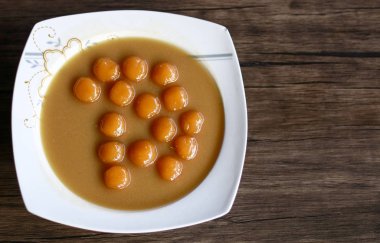 Ahşap arka plan üzerinde Biji. Biji hindistan cevizi soslu tatlı patates köfte olduğunu. Endonezya'da popüler tatlı ya da oruç kırmak için.