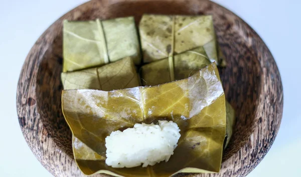 Fermented sticky (tape ketan) wrapped in guava leaves on white background.
