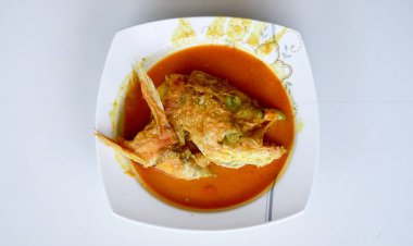 Beyaz arka planda Snapper Head Gulai (köri). Gulai zengin, baharatlı ve sulu köri içeren bir yiyecek türüdür..
