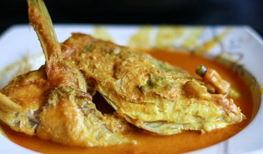 Siyah arka planda Snapper head gulai (köri). Gulai zengin, baharatlı ve sulu köri içeren bir yiyecek türüdür..