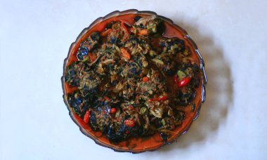 Beyaz arka planda Buntil. Buntil, papaya, cassava ya da taro yapraklarıyla sarılıp hindistan cevizi sütüyle kaynatılmış, rendelenmiş hindistan cevizi ve baharatla karıştırılmış geleneksel bir Java yemeğidir.