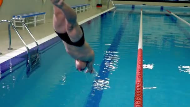 Плавець стрибає в спортивний басейн — стокове відео