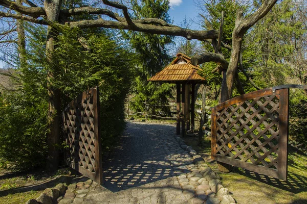 Wooden garden gates among trees grass and beautiful rock path covered with moss and sand