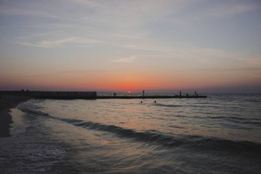 Parlak kırmızı güneşile kumlu kıyı 