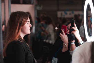 Kyiv, Ukrayna - 16 Eylül 2020: Uluslararası Güzellik Sanayi Fuarı InterCHARM. Herkes hazır makyajla modelin fotoğrafını çeker. Sahne ışıkları altında modellik yap. Makyaj ustası sınıfı.