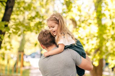  Baba ve küçük kızı sokakta parkta oynuyorlar, bir bebek babasının omuzlarında oturuyor, yakın plan, çocuk gülüyor, konsept mutlu babalar günü. Kaliteli fotoğraf