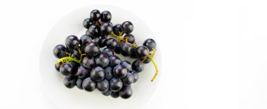 Bir kase ve beyaz zemin üzerine lezzetli taze siyah üzüm