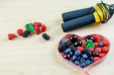 Bir grup böğürtlen, bantlama ve arka planda ip atlama. Sağlıklı yaşam tarzının sembolleri, uygun dengeli beslenme. 