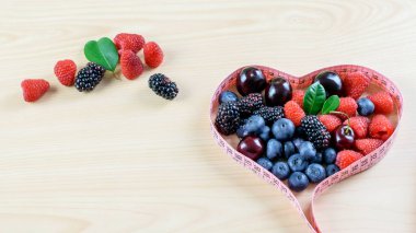 Ormanda taze meyve, ahududu, böğürtlen, ahşap arka planda böğürtlen, sağlıklı meyve diyetinin bir sembolü olarak bant kullanımı, kilo kaybı. 