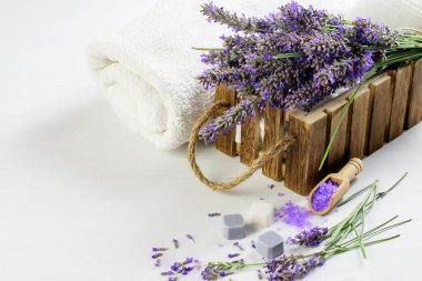 Lavanta çiçekleri, aromatik lavanta tuzu ve sabun ahşap arka planda beyaz havlular. Sağlık, kaplıca ve aromaterapi.