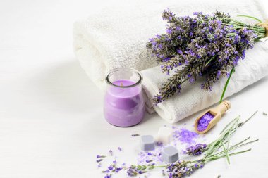 Lavanta çiçekleri, spa lavanta sabunu ve tuz, beyaz arka planda beyaz havlular. Spa aromaterapisi, sağlık hizmeti konsepti. 
