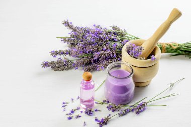 Lavanta tozu, havanda lavanta çiçeği, beyaz arka planda lavanta yağı ve mum. Cilt bakımı, aroma terapisi konsepti. 
