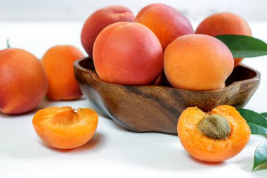 Beyaz arka plandaki ahşap kasede taze olgun kayısılar, yakın plan. Şükran Günü, yaz hasat konsepti. 