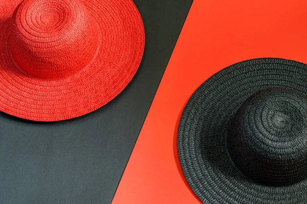Lady red hat on the black background and black red on the red background. Flat lay, top view. Fashion and beauty concept.