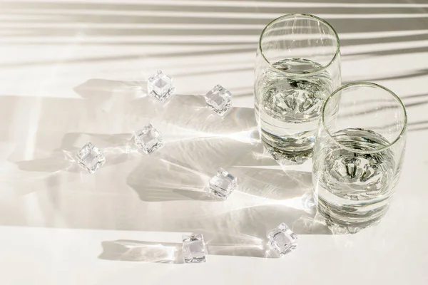 白色背景上的玻璃杯和冰块 长而硬的阴影 — 图库照片
