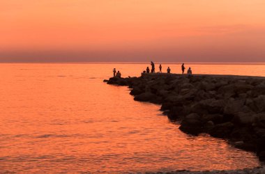 Denizde gün batımında insan siluetleri