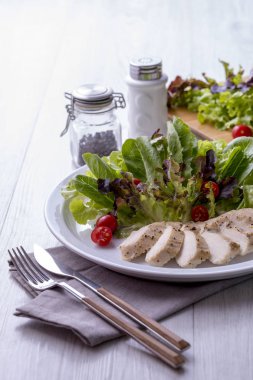 Çatal ve bıçak beyaz tabakta tavuk göğsü salatası