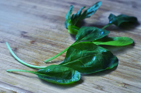 Taze ıspanak yaprakları. Ispanak salatası. Ispanak ve domates. Tahta kesme tahtası.