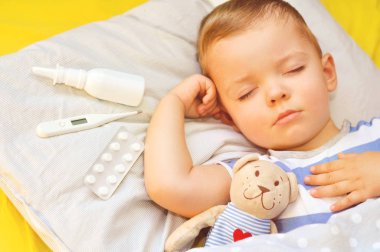 Küçük çocuk bir yastık ve ilaçlar ile termometre uyku yakındır