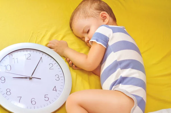 大きな時計と彼のベッドで眠るかわいい 歳男の子 — ストック写真