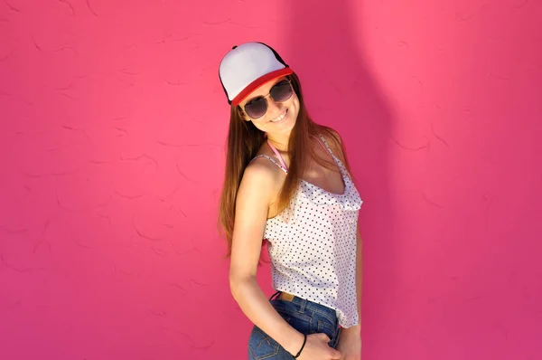 セクシー若いです女性でヒップホップスタイルの服とサングラスポーズに対してピンクの壁の背景 — ストック写真