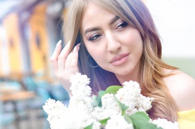 Pembe tonları ve güzel sarışın bukleler beyaz leylak bir buket ile poz profesyonel düğün makyaj ile güzel genç kadın.