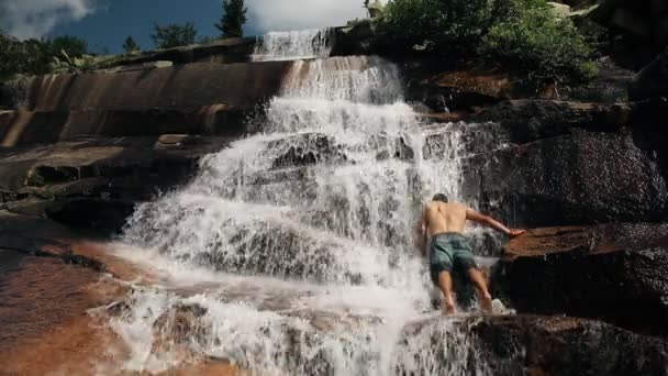 Odvážný mladík koupání v krásné horské vodopád. — Stock video