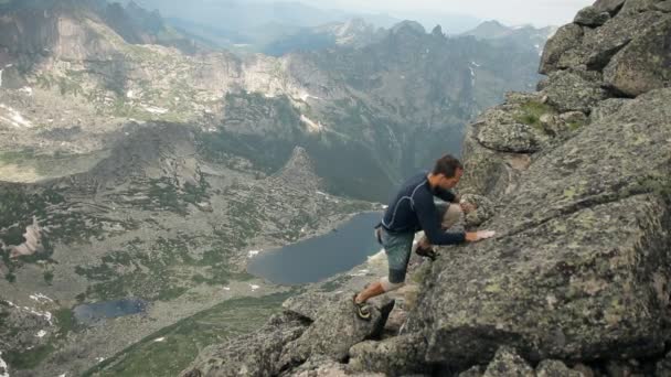 Ένα τολμηρό νεαρό αρσενικό ορειβάτης που σκαρφαλώνει στα βράχια. — Αρχείο Βίντεο