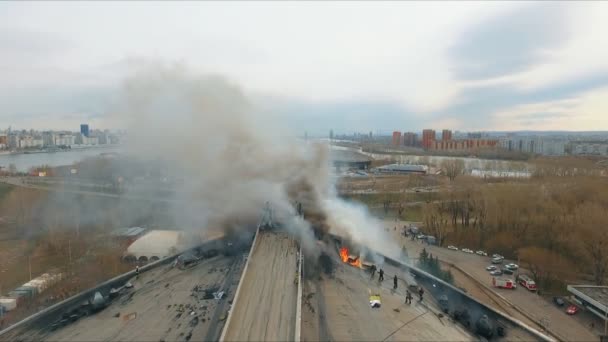 Luchtfoto van de moedige brandweerlieden die hun leven riskeren blussen een grote brand op het dak van het gebouw. — Stockvideo