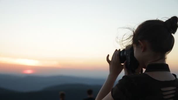 Het silhouet van een jonge vrouw die een foto van de zonsondergang. — Stockvideo